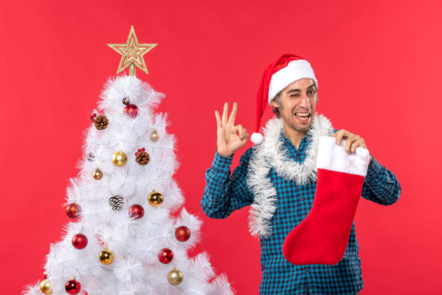 制作一个戴着圣诞老人帽子 穿着蓝色条纹衬衫的快乐的年轻人圣诞年轻人圣诞老人