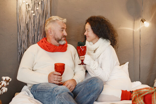 拥抱年龄和人的概念家里的老年夫妇穿着白色针织毛衣的女人浪漫坐着装饰