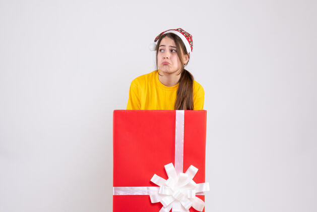 盒子戴圣诞帽的快乐女孩站在白色圣诞礼物后面丝带快乐大