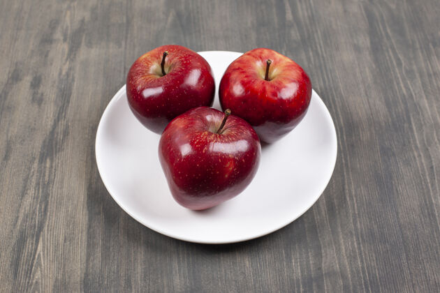 苹果一个白色的盘子 上面放着红色多汁的苹果高质量的照片收获木头多汁