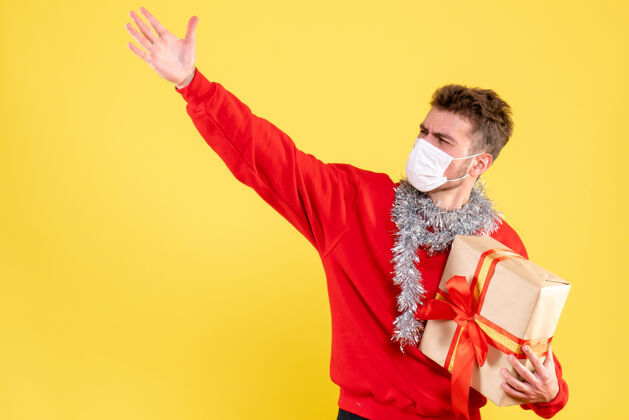 面具正面图：戴着无菌面具的年轻男性正在过圣诞节年轻男性不育礼物