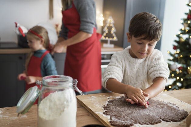 正面圣诞节期间做姜饼饼干的男孩制作装饰厨房