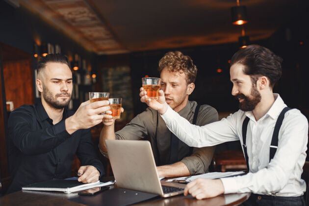 职业谈判中的商人坐在桌边喝酒的男人朋友们在聊天成人威士忌商人