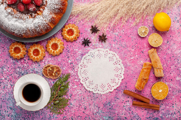 棉花俯瞰美味的草莓蛋糕与百吉饼饼干和一杯茶的粉红色背景蛋糕甜甜的甜甜饼干馅饼生的蛋糕茶