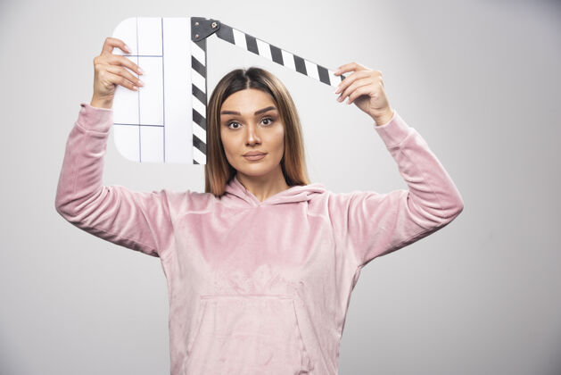 电影制作穿着粉色运动衫的金发女士拿着一块空白的隔板 看着里面拍板金发视频