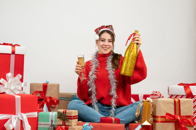 宗教戴着圣诞帽的女孩微笑着 手里拿着香槟和玻璃杯 围坐在白色的礼物旁边圣诞节礼物帽子