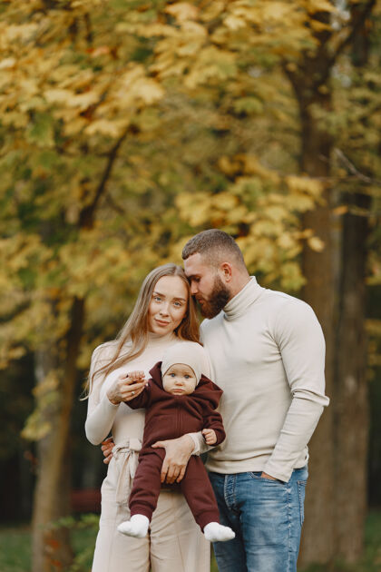 成人秋天公园里的一家人穿棕色毛衣的男人和父母在一起的可爱小女孩男人毛衣母亲
