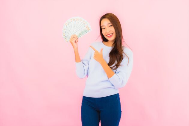 成人在粉红色的墙上画一幅美丽的亚洲年轻女子的画像 上面有很多现金和金钱手机赢彩票