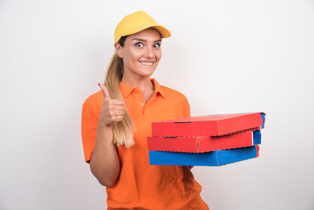 手势带着黄色帽子的送货员拿着披萨盒 竖起大拇指手掌快乐女性
