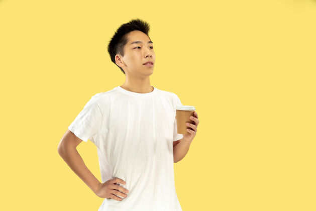 咖啡韩国年轻人的肖像穿白衬衫的男模喝咖啡 感觉快乐人类情感的概念 面部表情前视流行的颜色人模特展示