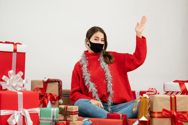 圣诞节穿着红色毛衣 戴着黑色面具的年轻女孩举起手围坐在白色的礼物旁边周围椅子提高
