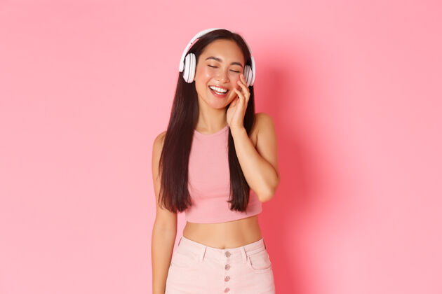现代一个戴着耳机听音乐的富有表情的年轻女子人物听力女性
