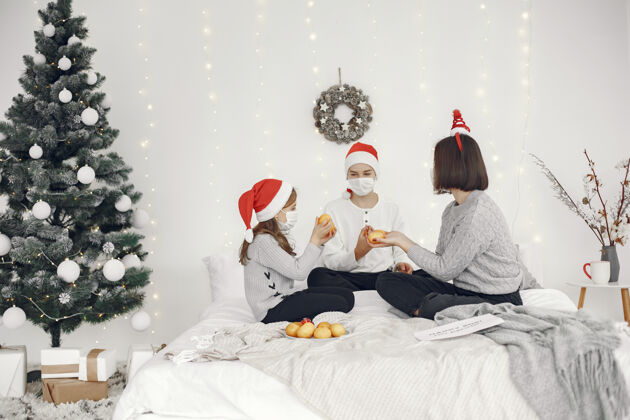 生病为圣诞节做准备的人两个母亲和他们的孩子玩耍冠状病毒隔离传统女儿花环