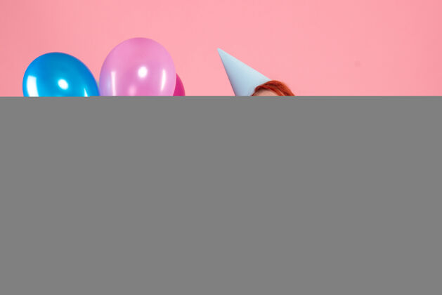 前面正面图是粉红色墙上戴着消毒面具手持彩色气球的年轻女子粉色庆祝不育