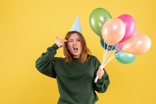 五颜六色正面图：带着彩色气球的年轻女性快乐女人一年