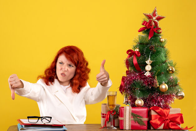 桌子女工人坐在桌子后面 手里拿着圣诞礼物和黄色的圣诞树女工人礼物黄色