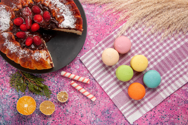 生的顶视图巧克力蛋糕 草莓和麦卡龙放在粉红色的桌子上 甜甜的饼干饼干巧克力饼干水果