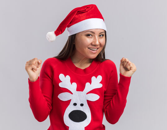 年轻兴奋的年轻亚洲女孩戴着圣诞帽和毛衣 在白色背景上显示“是”的手势毛衣女孩手势