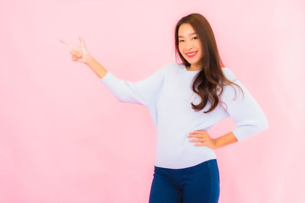 韩语美丽的亚洲年轻女子在粉红色的隔离墙上微笑中国人影子成功