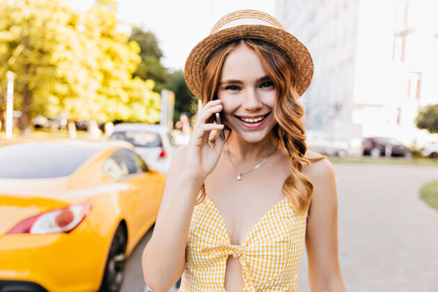 稻草优雅的金发女孩戴着复古的帽子在夏日周末打电话穿着黄色服装的可爱的白色女模特正在享受早晨的散步户外配件快乐