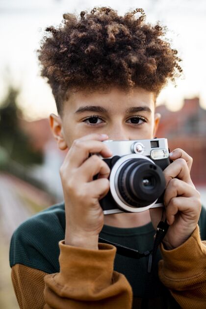 男孩小男孩拿着相机在外面拍照童年垂直无忧无虑