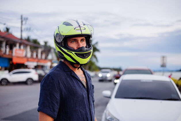 比赛日落时分 在泰国繁忙的公路边 一位戴着黄色头盔的男子的画像引擎滑板车出租