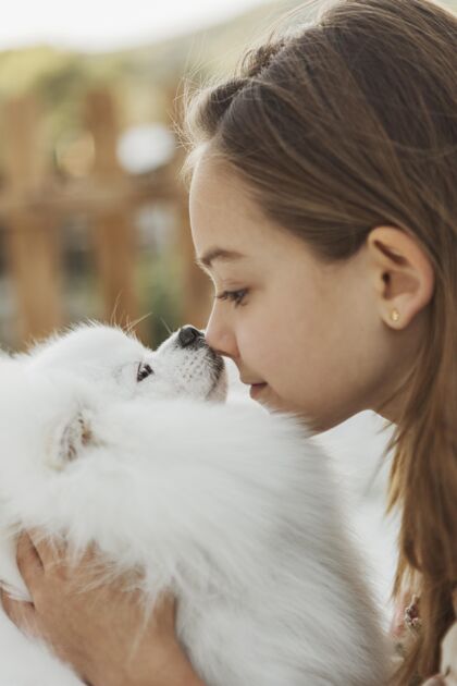 动物侧视图女孩和她的狗碰鼻子狗孩子小狗
