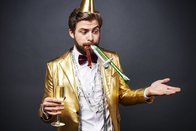 庆祝带着香槟长笛站在派对吹风机旁的惊讶男人跳舞除夕夜聚会