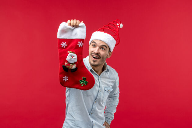袜子红墙上穿着圣诞袜的年轻人的正视图帽子可爱年轻