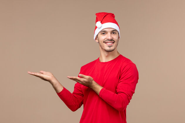 工人正面图：棕色空间上穿着红色圣诞斗篷的年轻男性圣诞节快乐成人