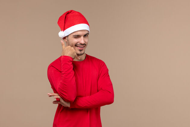 肖像正面图棕色背景上的年轻男性带着微笑的表情圣诞假期感慨年轻表情男人