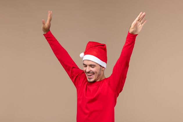 快乐正面图年轻男子在棕色背景上跳舞圣诞节情感假期肖像微笑乐趣
