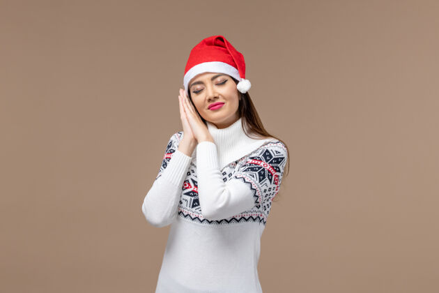 人物前视图年轻女性试图在棕色背景上的红色帽子睡觉情绪圣诞节新年可爱微笑模特