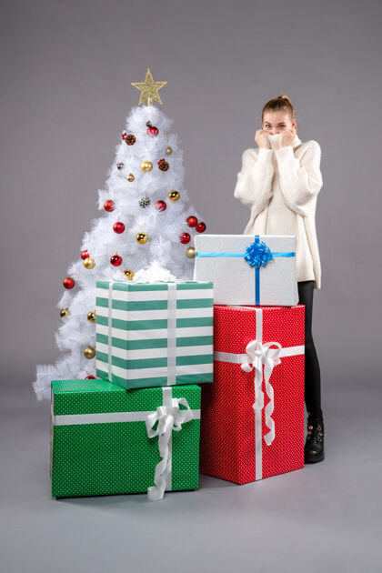 圣诞树在灰色地板上的圣诞礼物周围的年轻女性礼物包圣诞礼物
