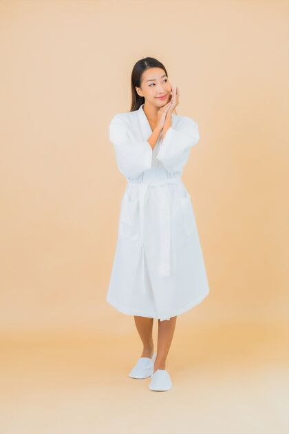 诊所肖像美丽的亚洲年轻女子穿着米色的微笑浴袍自然浴缸看