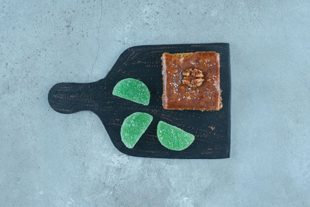 糖在大理石表面的一块黑色木板上放上烤面包和果冻糖果美味核桃甜点