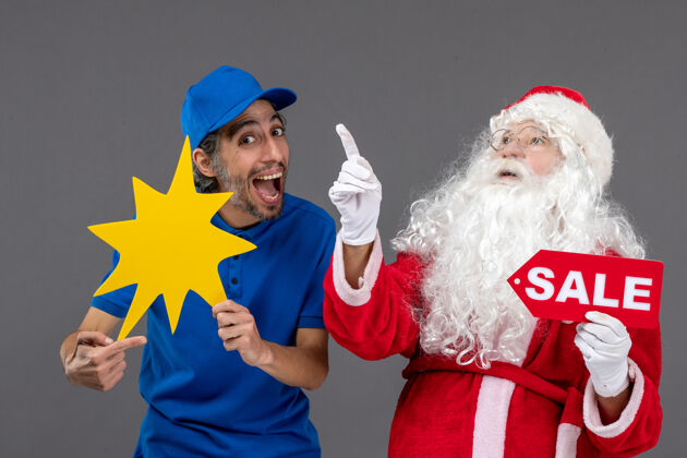 销售圣诞老人的正面图 男性信使手持销售横幅 灰色墙上有黄色标志人十二月前面