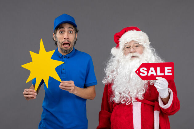销售圣诞老人的正面图 男性信使手持销售横幅 灰色墙上有黄色标志圣诞举行圣诞快乐