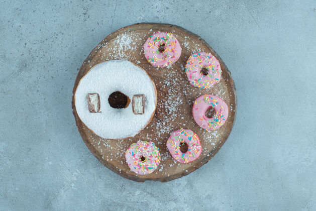 视图在大理石的木板上排列一个大的和几个小的甜甜圈烘焙食品美味烘焙