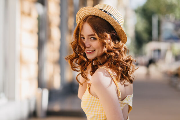 公园迷人的黑卷发女孩在温暖的夏日里在户外嬉戏戴着帽子和黄色连衣裙的姜黄色女模特在城市街道上欢笑黄色情感放松