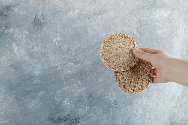 脆的女人的手拿着酥脆的面包放在大理石表面健康食物有机