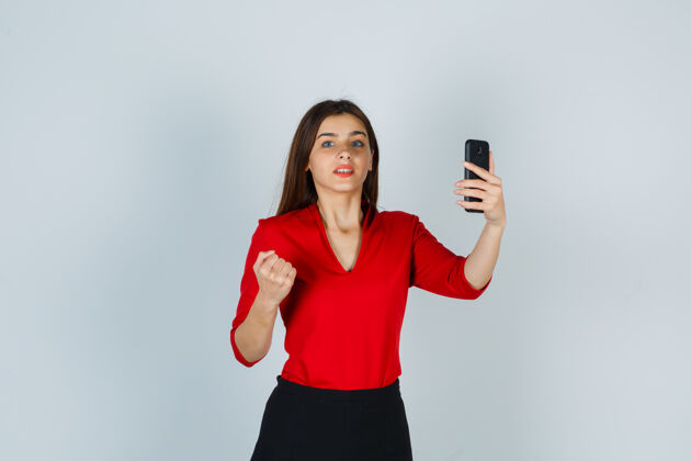模特穿着红色上衣的年轻女士手持手机举起拳头自然女士表情