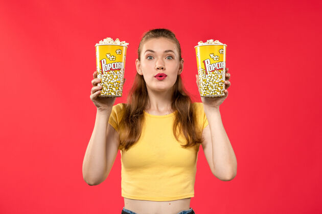 漂亮正面图年轻的女性在电影院拿着爆米花包在红墙电影院看电影 电影院小吃女性趣味电影小吃电影剧院
