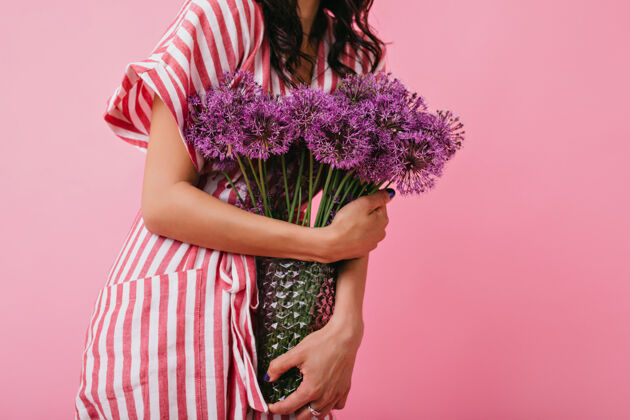 时尚花瓶特写中紫罗兰野花的镜头穿着粉色太阳裙的女孩手持花束女士女性丁香