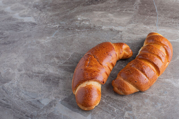 两个两个甜羊角面包放在大理石桌上食物牛角面包面包房