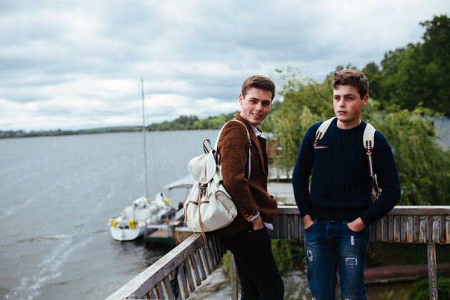 帅气两个年轻人站在码头上 其中一个转过头来时尚使用男性