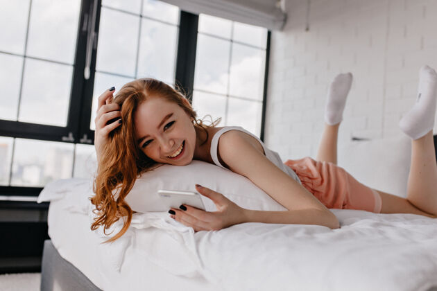 寒冷安静的欧洲女孩躺在床上穿着白袜子的姜女人在家里度过早晨的室内照片年轻快乐红发
