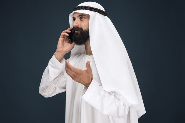 表情深蓝色工作室背景的阿拉伯沙特男人阿拉伯搞笑传统