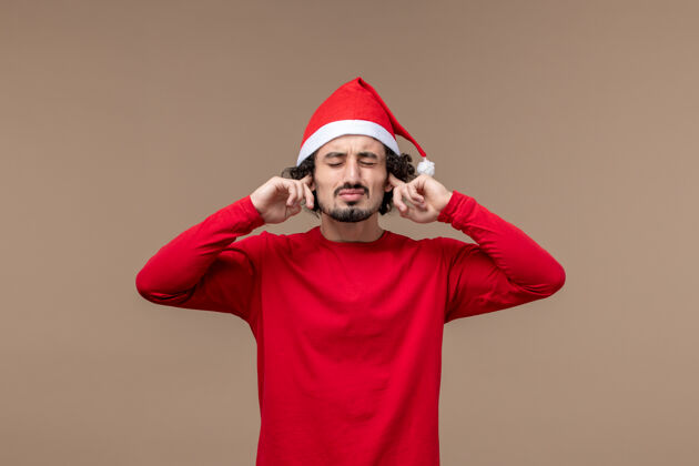 观点正面图：一个年轻人在圣诞假期的棕色背景上磕着耳朵男人肖像微笑