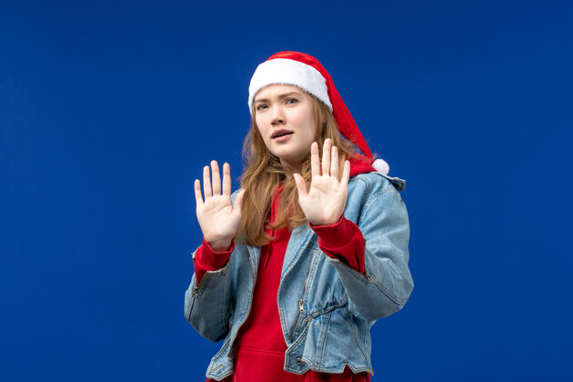 年轻女性蓝色背景上表情迷茫的年轻女性圣诞情感开朗球员微笑